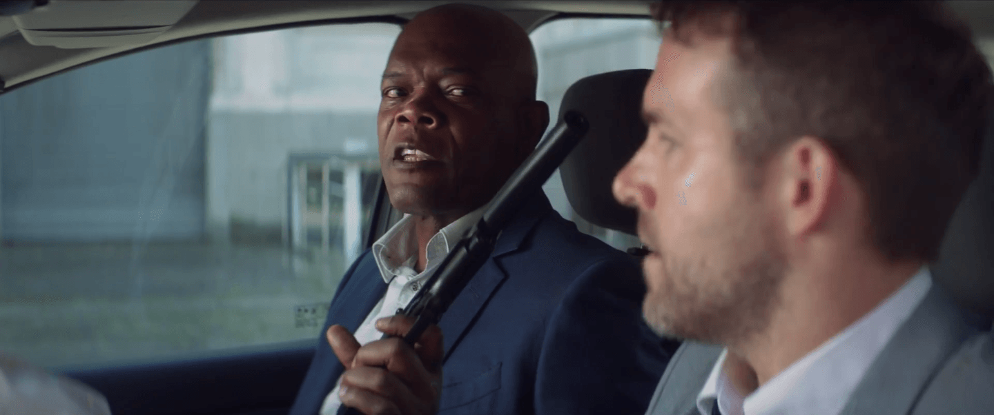 Samuel L. Jackson pointing a gun at Ryan Reynolds in THE HITMAN'S BODYGUARD.