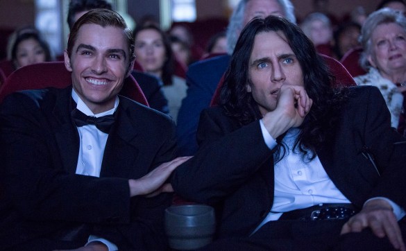 Dave Franco laughing in a movie theater with James Franco in THE DISASTER ARTIST.