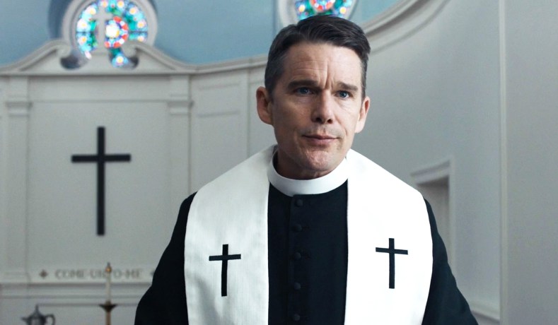 Ethan Hawke dressed as a minister in a church with his lips pursed in Paul Schrader's movie First Reformed.