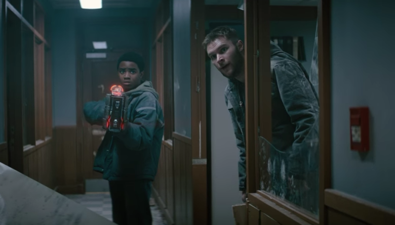 Myles Truitt aims a very big laser gun down a hallway to protect his brother played by Jack Reynor in the movie Kin