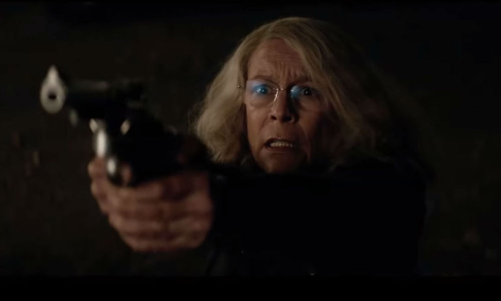 Jamie Lee Curtis looking worried pointing a revolver at the camera in the 2018 film Halloween