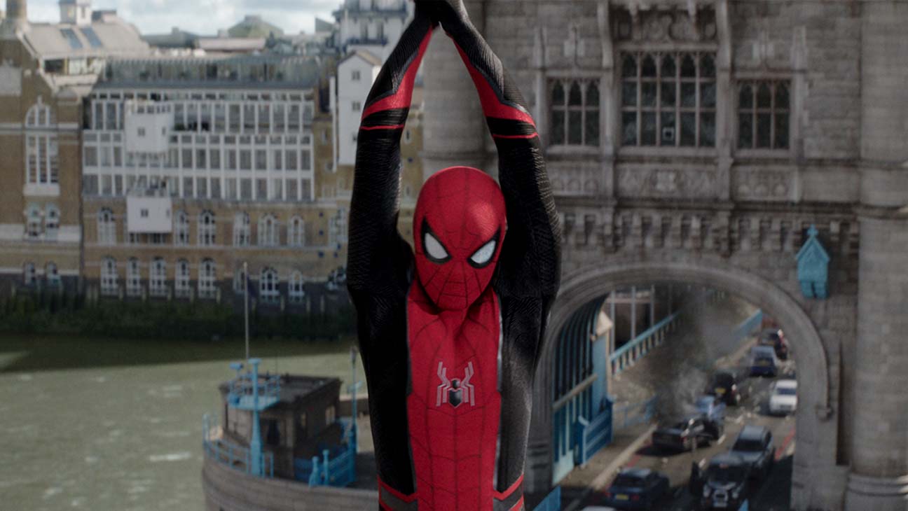 Spiderman swings at the camera holding a web with both hands over his head in the movie Spider-Man: Far From Home