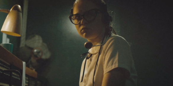 Sierra McCormick looks skeptically while wearing her switchboard operator headset in the movie The Vast of Night