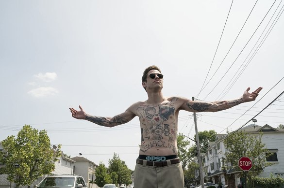 Pete Davidson shirtless with sunglasses and arms outstretched in the movie The King of Staten Island