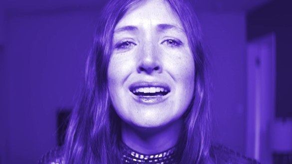 Kate Lyn Sheil faces the camera, tinged in blue light in the film She Dies Tomorrow