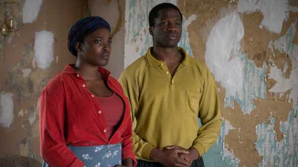 Wunmi Mosaku and Sope Dirisu stand next to walls with peeled-off wallpaper in film His House