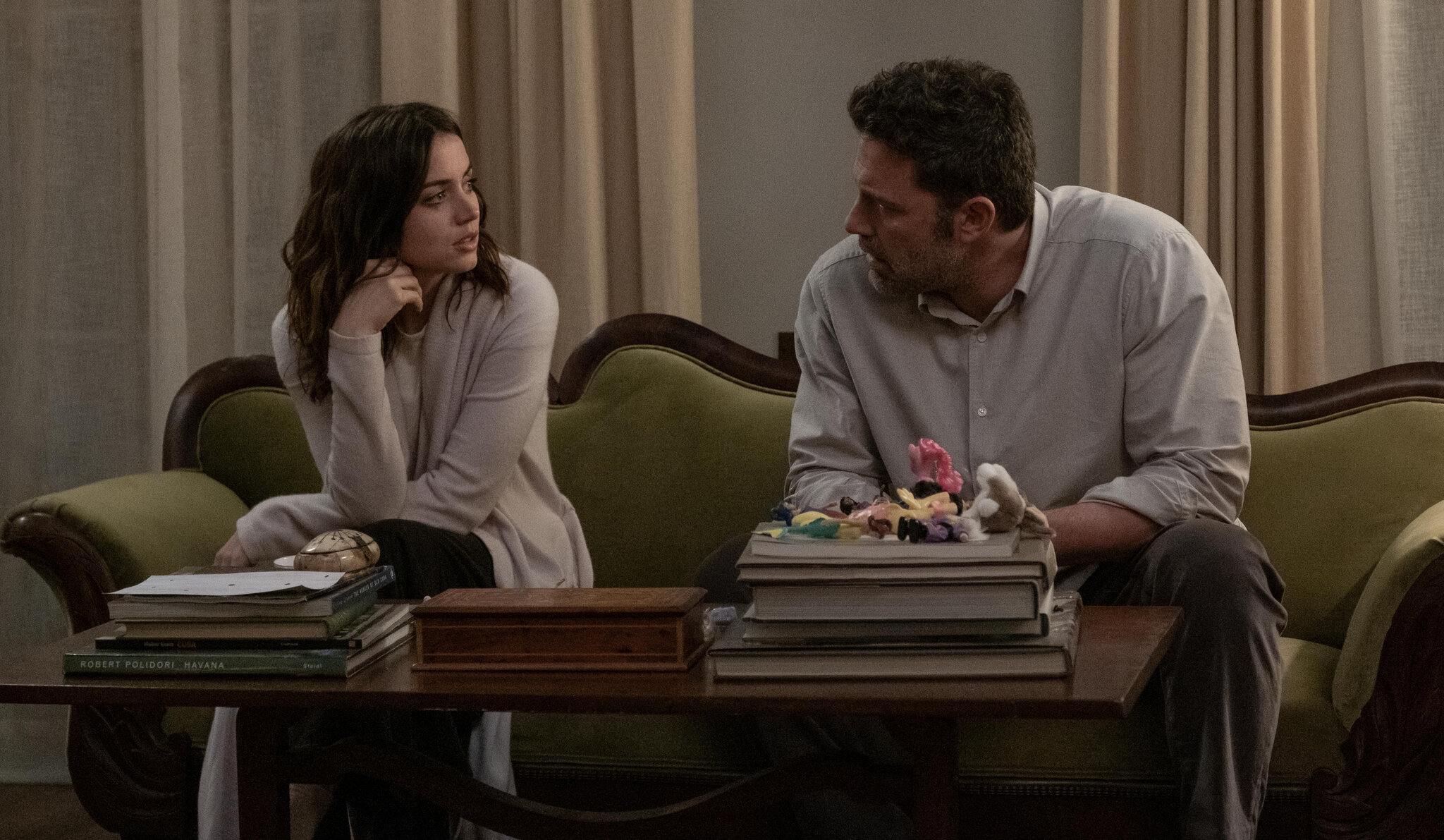 Ana de Armas sits on a couch looking imploringly at Ben Affleck in the movie Deep Water